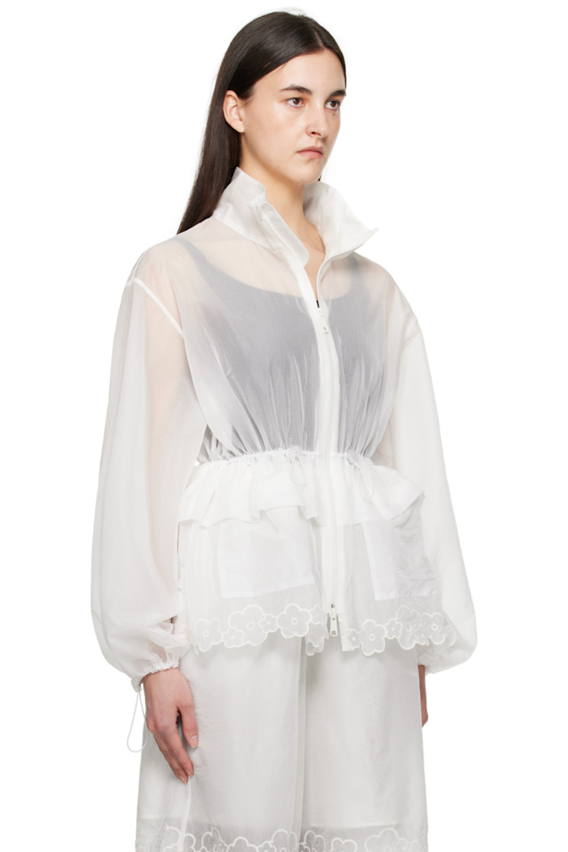 Semi-sheer nylon ripstop jacket.

· Stand collar
· Two-way zip closure
· Bungee-style drawstring at waist and cuffs
· Ruffled trim at waist
· Flap pockets
· Embroidered floral pattern and scalloped edge at hem
· Peplum hem

Supplier color: White