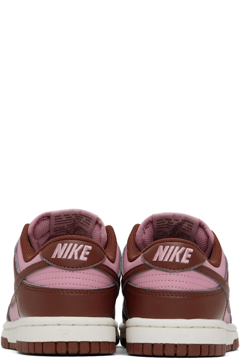 Low-top buffed leather sneakers in pink and brown.

· Perforated detailing at toe
· Lace-up closure
· Logo patch at padded tongue
· Padded collar
· Swoosh appliqué at sides
· Logo embroidered at heel tab
· Mesh lining
· Textured foam rubber midsole
· Treaded rubber sole

Please note that this item may be shipped only within North America.

Supplier color: White/Elemental pink/Dark pony