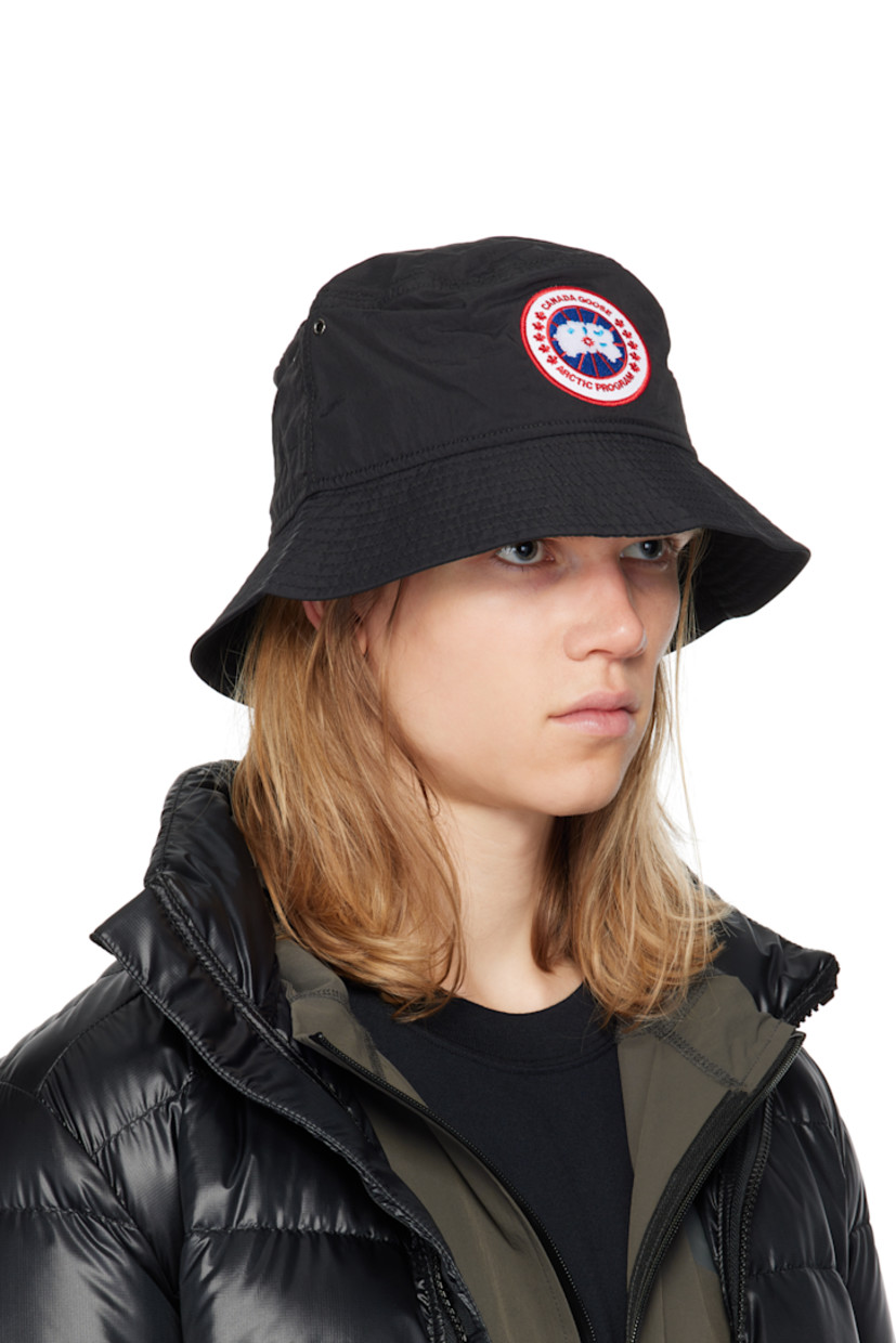 Nylon taffeta bucket hat in black.

· Lightweight, water-repellent, windproof, and breathable
· Metal eyelets at crown
· Embroidered logo patch at face
· Reflective trim at quilted brim
· Bungee-style drawstring at back face
· Mesh lining

Supplier color: Black