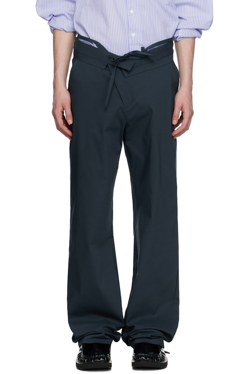 Plain-woven stretch cotton-blend trousers.

· Belt-style strap and raw edges at layered waistband
· Drawstring at foldover waistband
· Three-pocket styling
· Offset zip fly
· Self-tie straps at cuffs for alternate styling

Supplier color: Dark blue