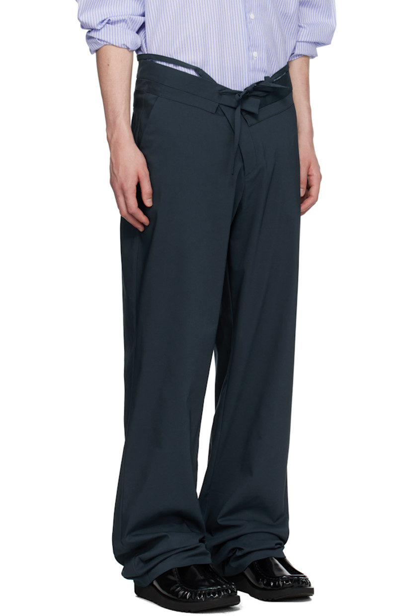 Plain-woven stretch cotton-blend trousers.

· Belt-style strap and raw edges at layered waistband
· Drawstring at foldover waistband
· Three-pocket styling
· Offset zip fly
· Self-tie straps at cuffs for alternate styling

Supplier color: Dark blue