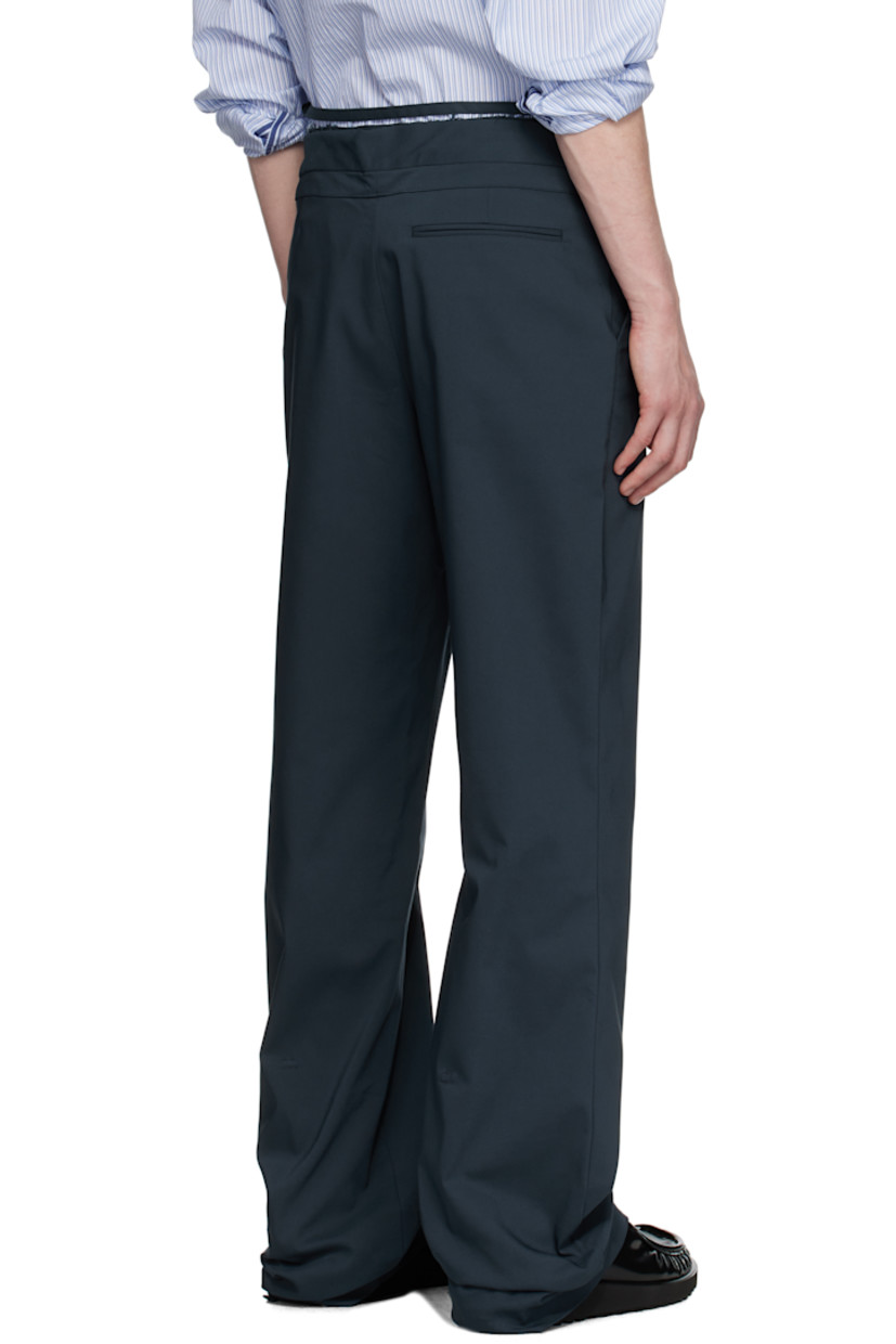 Plain-woven stretch cotton-blend trousers.

· Belt-style strap and raw edges at layered waistband
· Drawstring at foldover waistband
· Three-pocket styling
· Offset zip fly
· Self-tie straps at cuffs for alternate styling

Supplier color: Dark blue