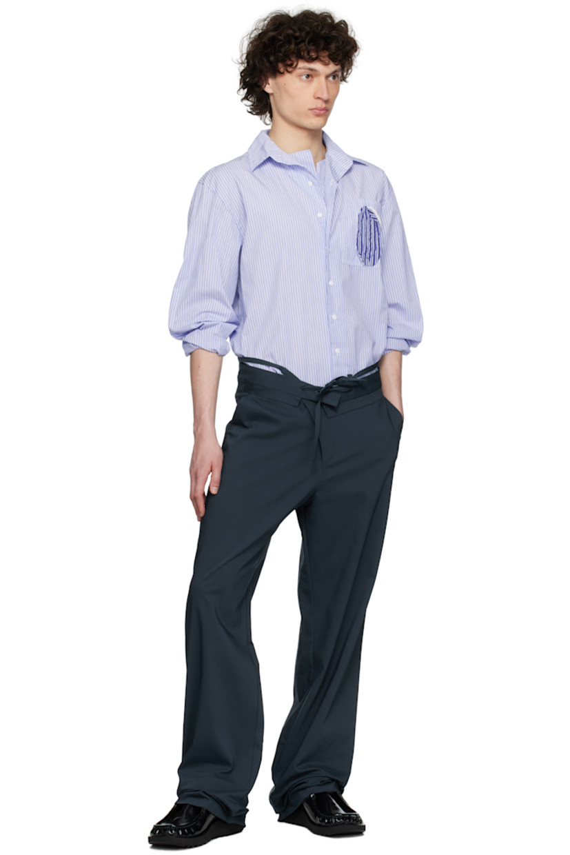 Plain-woven stretch cotton-blend trousers.

· Belt-style strap and raw edges at layered waistband
· Drawstring at foldover waistband
· Three-pocket styling
· Offset zip fly
· Self-tie straps at cuffs for alternate styling

Supplier color: Dark blue