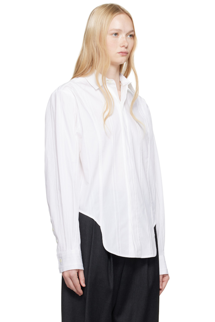 Plain-woven cotton shirt. Pinched seams throughout.

· Spread collar
· Concealed button closure
· Asymmetric cropped hem
· Pleats at buttoned barrel cuffs
· Frayed flag with topstitching at back yoke
· Box pleats at back yoke

Supplier color: White
