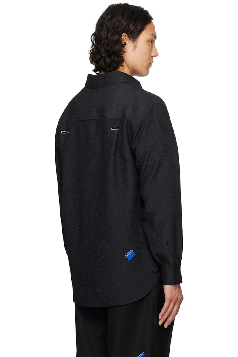 Oversized and crinkled plain-woven polyester shirt.

· Spread collar
· Button closure
· Box pleat at patch pockets
· Concealed double-button barrel cuffs
· Twin pleats with topstitching at back yoke
· Frayed appliqué at back hem

Supplier color: Noir