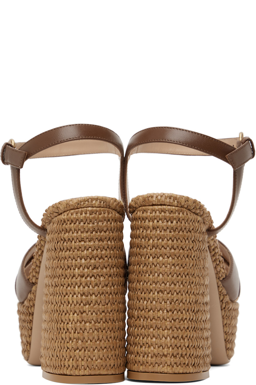 Handcrafted nappa leather heeled sandals in brown.

· Open toe
· Crisscrossing straps at vamp
· Pin-buckle ankle strap
· Logo stamp at padded footbed
· Buffed leather lining
· Woven raffia heel and platform midsole
· Block heel with rubber injection
· Leather sole
· Platform: H2"
· Heel: H4.75"

Supplier color: Cuoio/Cuoio