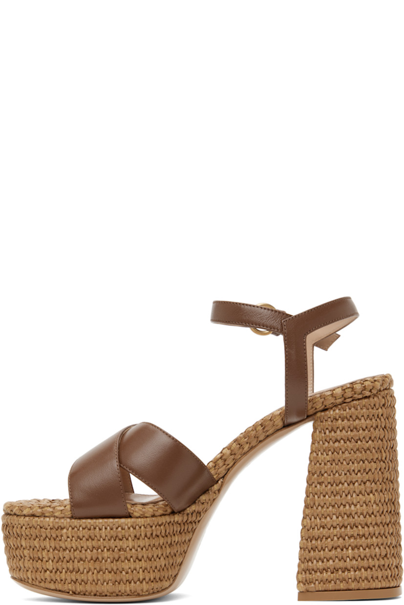 Handcrafted nappa leather heeled sandals in brown.

· Open toe
· Crisscrossing straps at vamp
· Pin-buckle ankle strap
· Logo stamp at padded footbed
· Buffed leather lining
· Woven raffia heel and platform midsole
· Block heel with rubber injection
· Leather sole
· Platform: H2"
· Heel: H4.75"

Supplier color: Cuoio/Cuoio