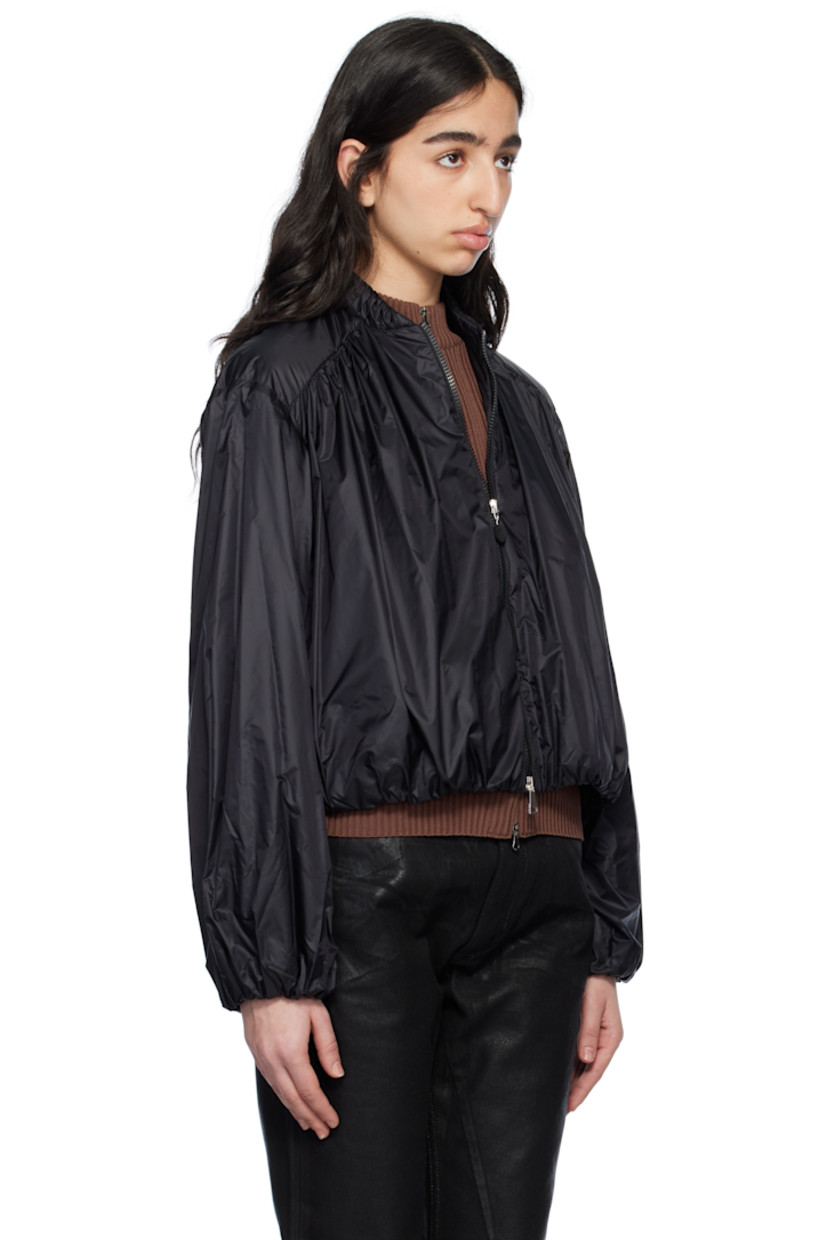 Lightweight nylon longue saison jacket. Gathering throughout. 

· Stand collar 
· Two-way zip closure
· Zip pockets
· Elasticized hem and cuffs
· Embroidered logo patch at sleeve
· Full taffeta lining

Supplier color: Black