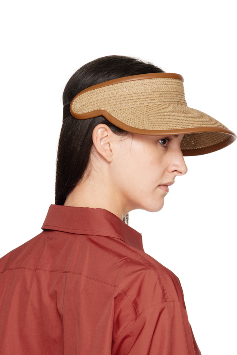 Woven paper visor. 

· Curved brim
· Logo hardware at side
· Adjustable elasticized cinch strap at back face
· Satin browband

Supplier color: Tobacco