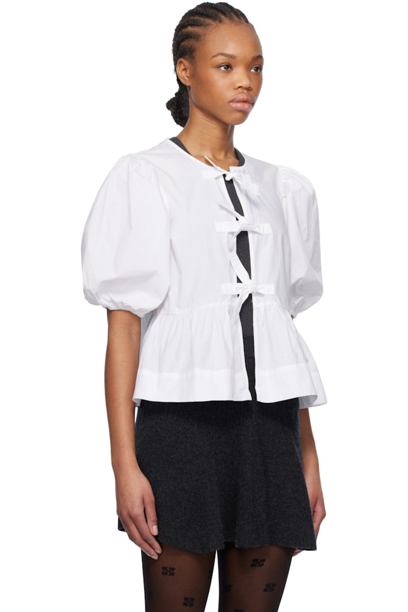 Organic cotton poplin blouse. Gathering throughout. 

· Crewneck
· Self-tie fastenings at open front
· Darts at chest
· Peplum hem
· Puff sleeves
· Elasticized cuffs

Supplier color: Bright white