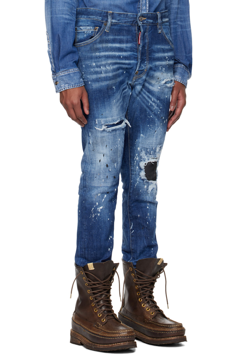 Stretch denim jeans. Fading, distressing, whiskering, and paint splatter throughout. 

· Belt loops
· Five-pocket styling
· Logo flag at button-fly
· Calfskin patch at knee
· Raw edge at cuffs
· Calfskin logo patch at back waistband
· Logo-engraved silver- and copper-tone hardware
· Contrast stitching in tan

Supplier color: Navy