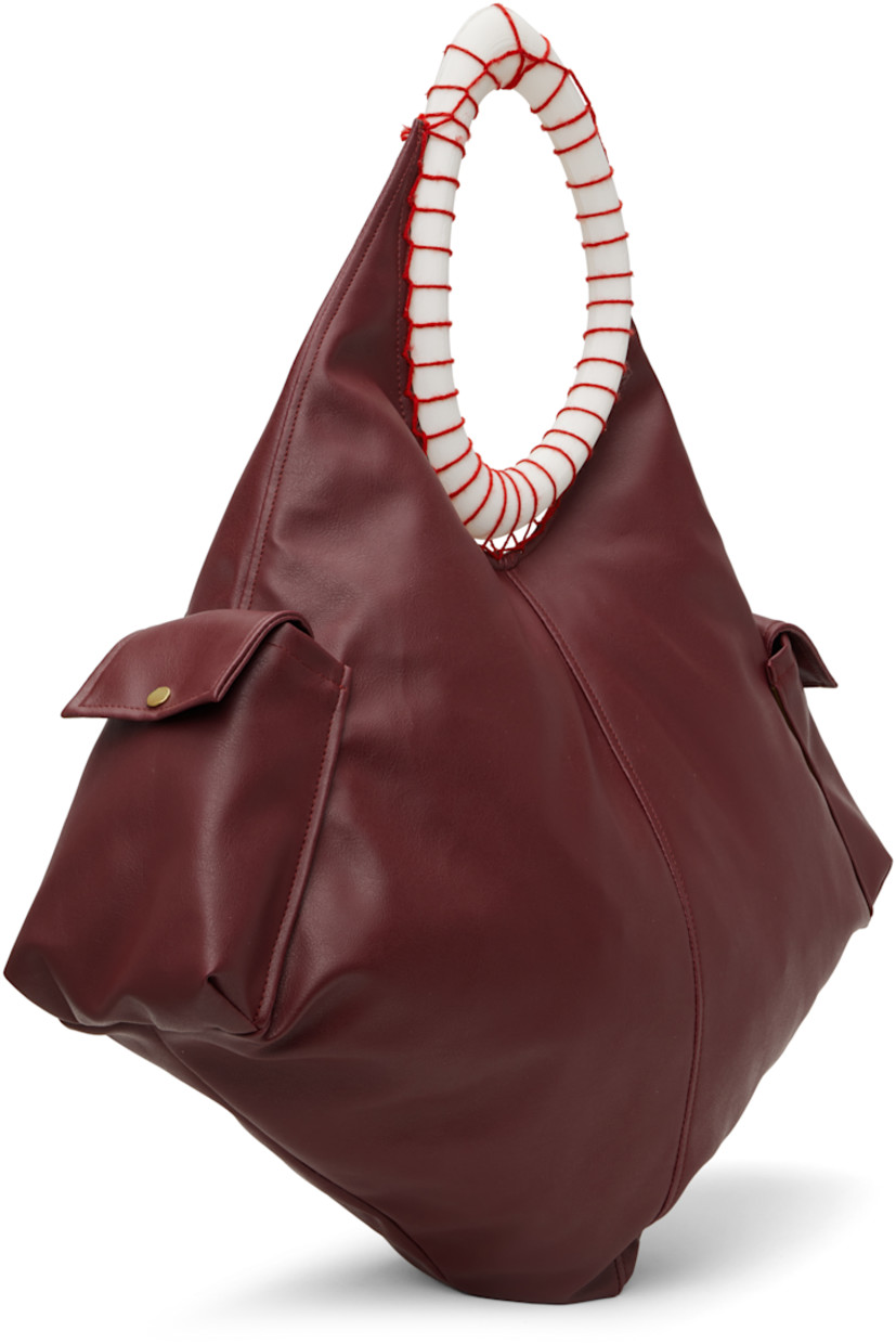 Grained leather tote in burgundy.

· 3D-printed PLA shoulder strap
· Flap pocket at sides
· Zip closure
· Brushed twill lining
· Flannel lining
· H18" x W23" x D6"
· Total height: H29"

Supplier color: Burgundy