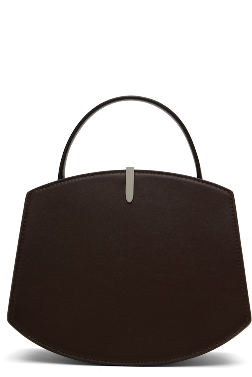 Buffed calfskin top handle bag in brown.

· Burnished edges throughout
· Fixed carry handle
· Silver-tone hardware at face
· Accordion panel at sides
· Logo stamp at back face
· Magnetic tab closure
· Card slot at two-compartment interior
· Buffed calfskin lining
· H6.75" x W8.25 x D4"
· Total height: H9.5"

Supplier color: Coffee
