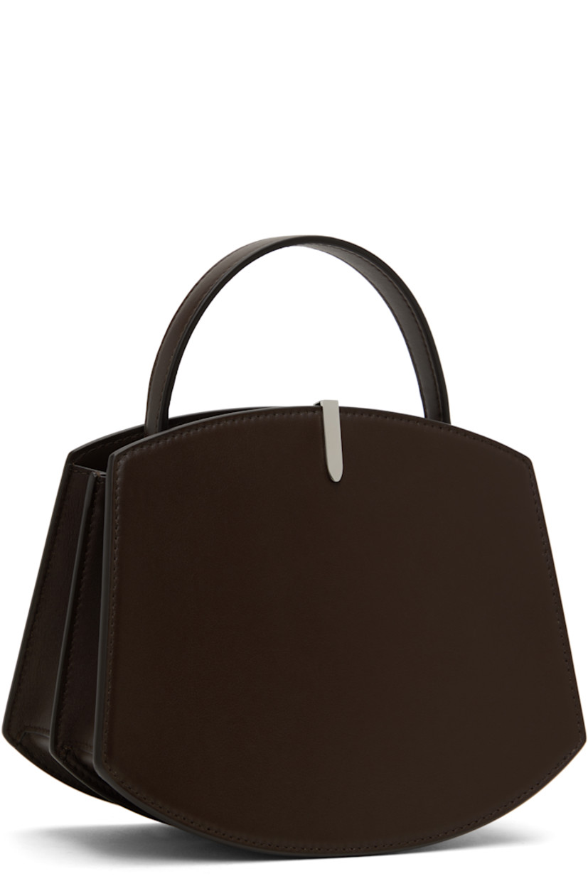 Buffed calfskin top handle bag in brown.

· Burnished edges throughout
· Fixed carry handle
· Silver-tone hardware at face
· Accordion panel at sides
· Logo stamp at back face
· Magnetic tab closure
· Card slot at two-compartment interior
· Buffed calfskin lining
· H6.75" x W8.25 x D4"
· Total height: H9.5"

Supplier color: Coffee