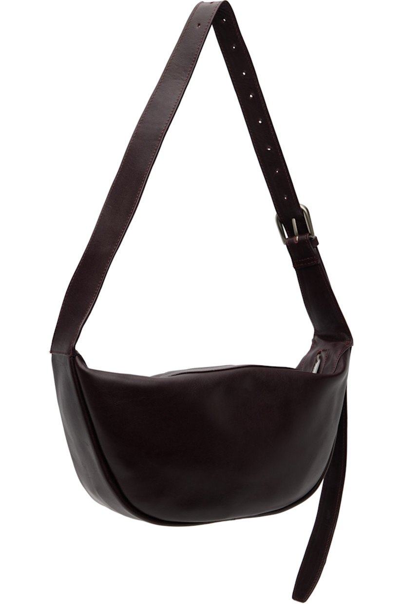Vegetable-tanned buffed leather shoulder bag.

· LWG-certified leather
· Adjustable pin-buckle shoulder strap
· Zip closure
· Goatskin suede lining
· H7" x W13" x D3.5"

Supplier color: Bordeaux