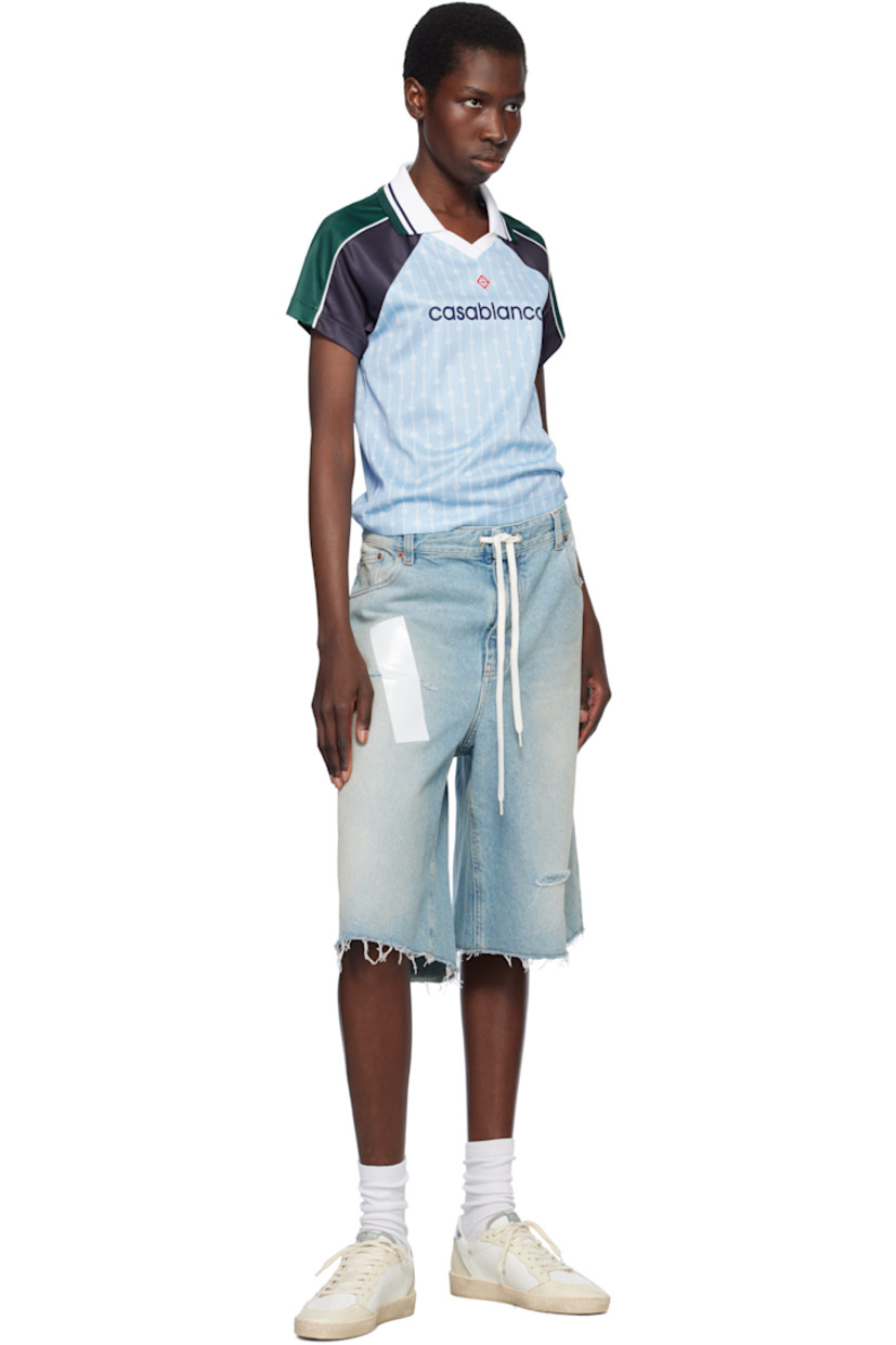 Polyester mesh T-shirt. Logo graphic pinstripes printed throughout.

· Striped rib-knit spread collar at V-neck
· Embroidered logo patch at chest
· Logo printed at front 
· Piping at raglan sleeves

Supplier color: Blue