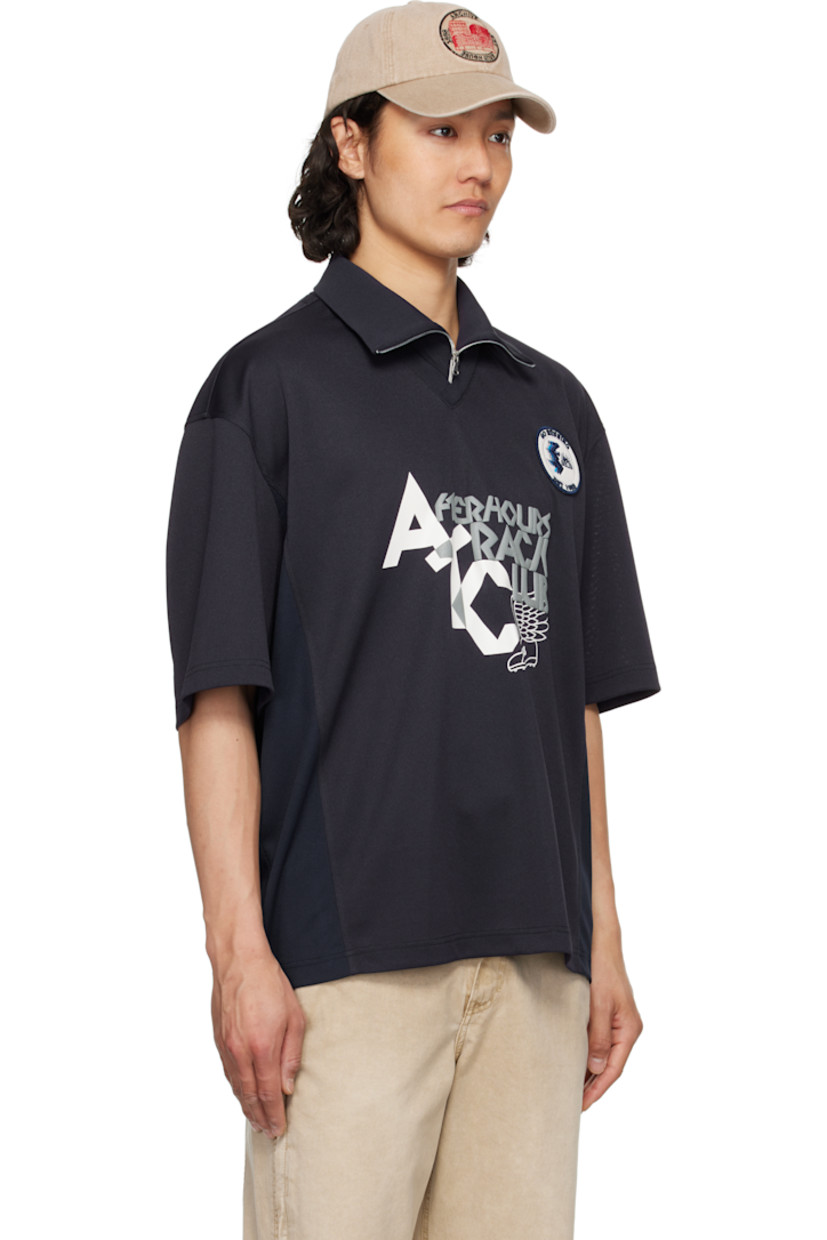 Polyester piqué polo. 

· Rib-knit spread collar and V-neck
· Half-zip closure
· Logo embroidered at collar
· Logo graphic patch at chest
· Text and graphic printed and bonded at front
· Mesh panel and vent at side seams
· Dropped shoulders

Supplier color: Navy