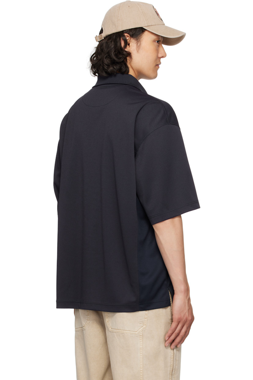 Polyester piqué polo. 

· Rib-knit spread collar and V-neck
· Half-zip closure
· Logo embroidered at collar
· Logo graphic patch at chest
· Text and graphic printed and bonded at front
· Mesh panel and vent at side seams
· Dropped shoulders

Supplier color: Navy