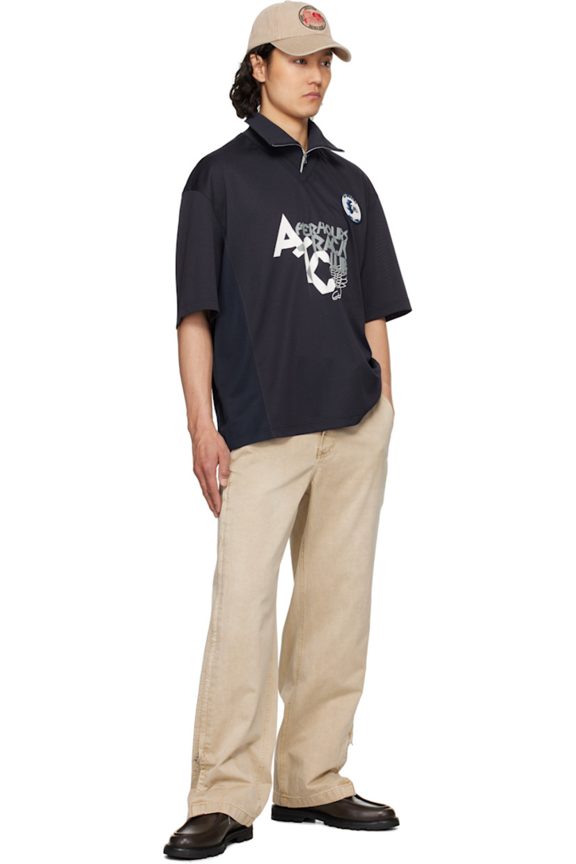 Polyester piqué polo. 

· Rib-knit spread collar and V-neck
· Half-zip closure
· Logo embroidered at collar
· Logo graphic patch at chest
· Text and graphic printed and bonded at front
· Mesh panel and vent at side seams
· Dropped shoulders

Supplier color: Navy