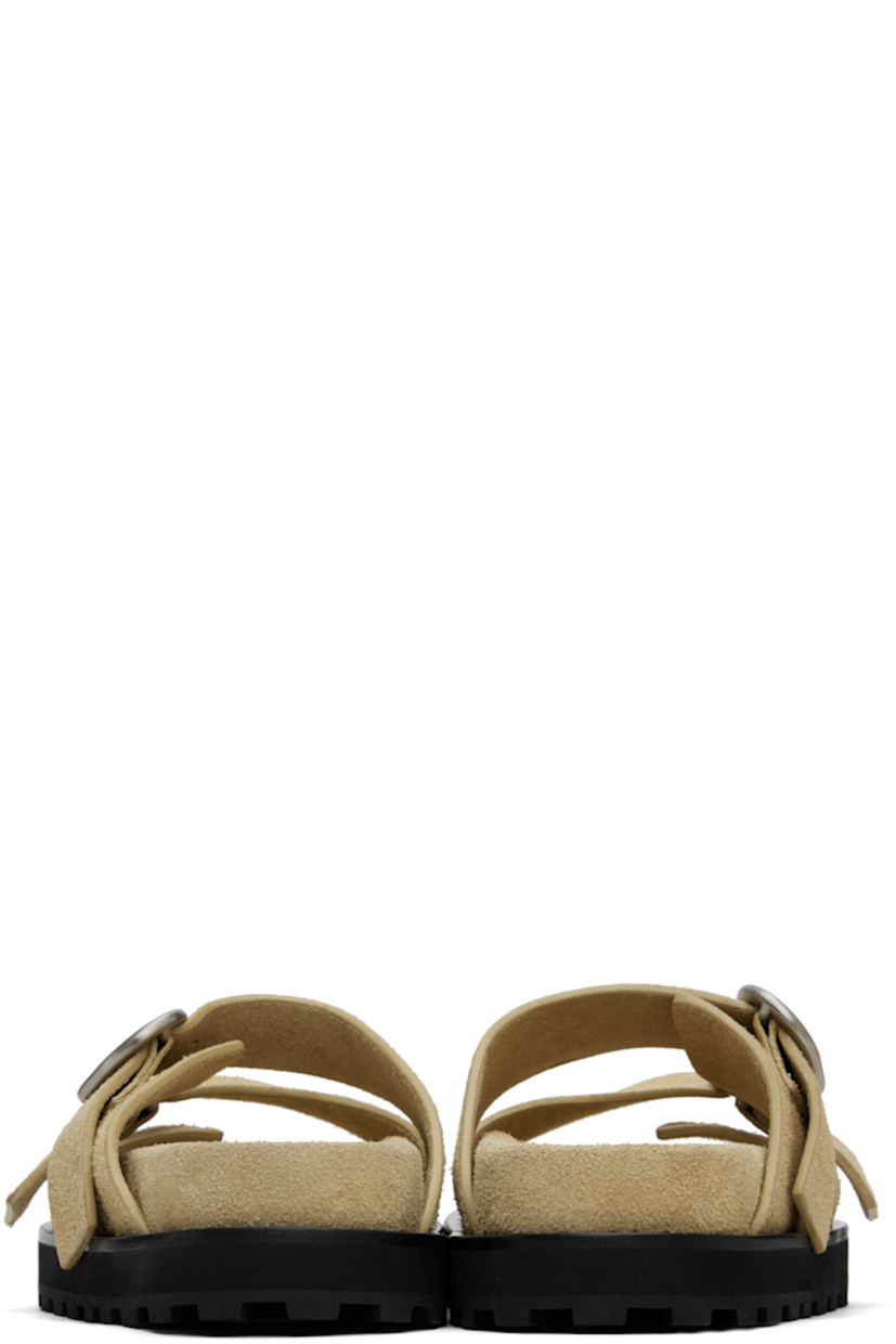 Suede slip-on flat sandals in beige.

· Open toe
· Adjustable pin-buckle straps at vamp
· Logo patch at molded footbed
· Foam rubber midsole
· Lugged rubber sole

Supplier color: Barley