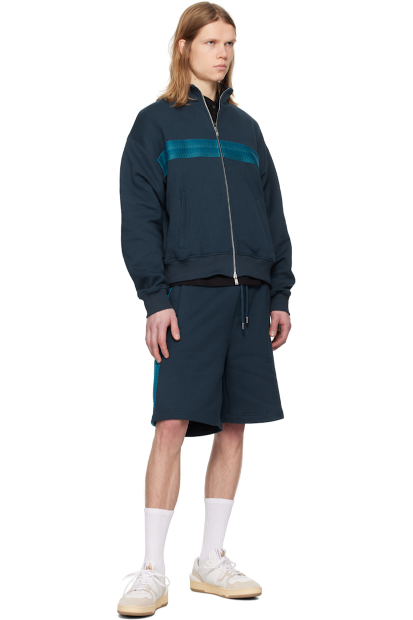Cotton fleece track jacket.

· Stand collar
· Two-way zip closure
· Chevron-woven webbing trim at front
· Welt pockets
· Rib-knit hem and cuffs
· Logo embroidered at back collar

Supplier color: Petrol blue