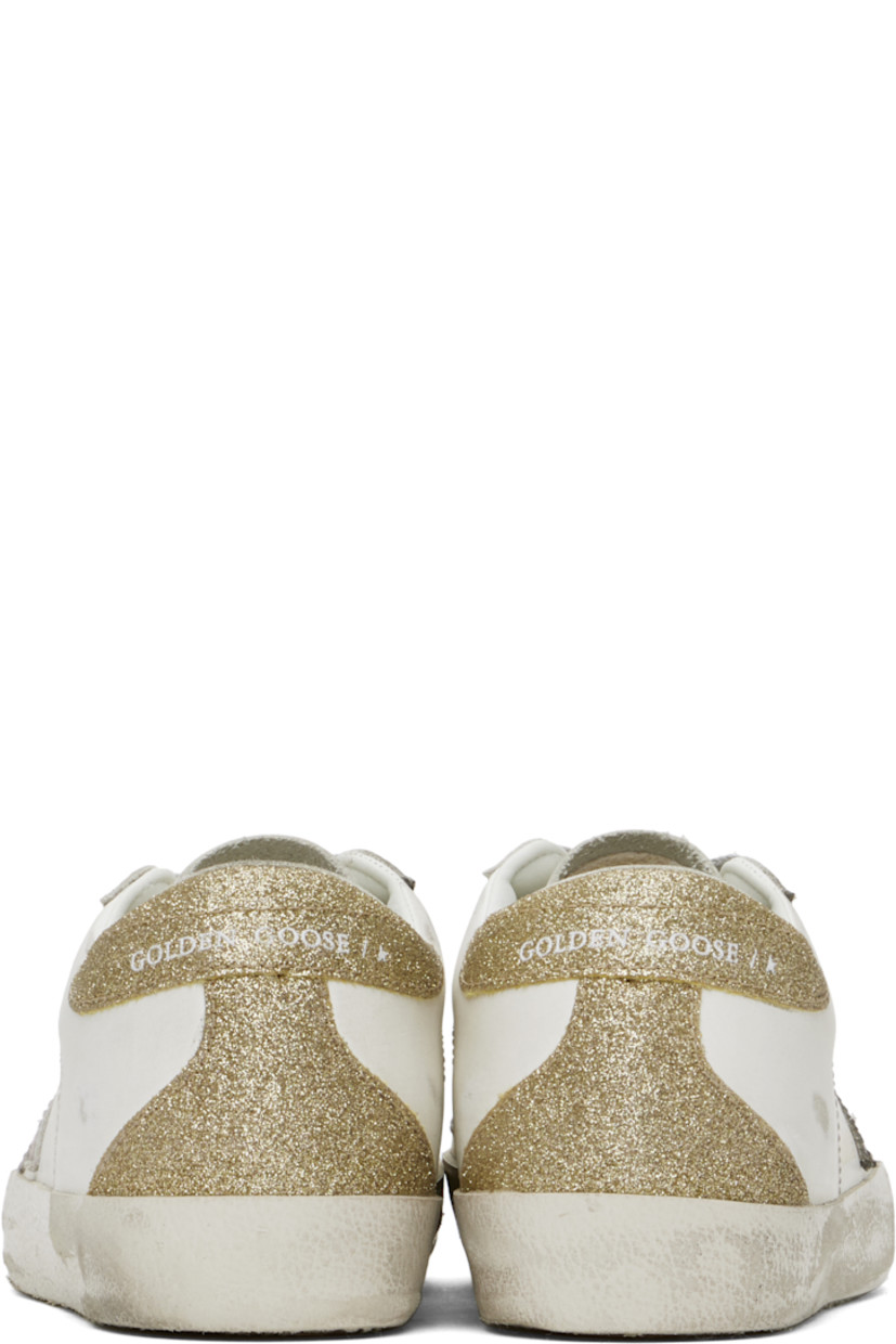 Low-top buffed leather sneakers in white, purple, and gold tone.

· Distressing and smudging throughout
· Lace-up closure
· Logo stamp at tongue
· Padded collar
· Signature star appliqué at outer side
· Logo stamp at outer side
· Perforated detailing at sides
· Logo embossed at glittered heel tab
· Buffed leather, suede, and terrycloth lining
· Textured rubber midsole
· Treaded rubber sole

Supplier color: White/Lilac/Gold
