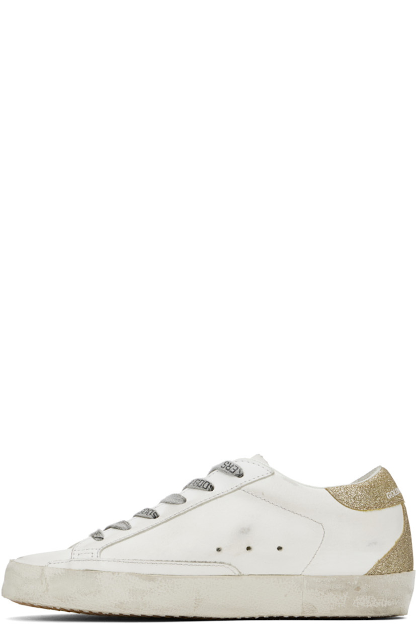Low-top buffed leather sneakers in white, purple, and gold tone.

· Distressing and smudging throughout
· Lace-up closure
· Logo stamp at tongue
· Padded collar
· Signature star appliqué at outer side
· Logo stamp at outer side
· Perforated detailing at sides
· Logo embossed at glittered heel tab
· Buffed leather, suede, and terrycloth lining
· Textured rubber midsole
· Treaded rubber sole

Supplier color: White/Lilac/Gold