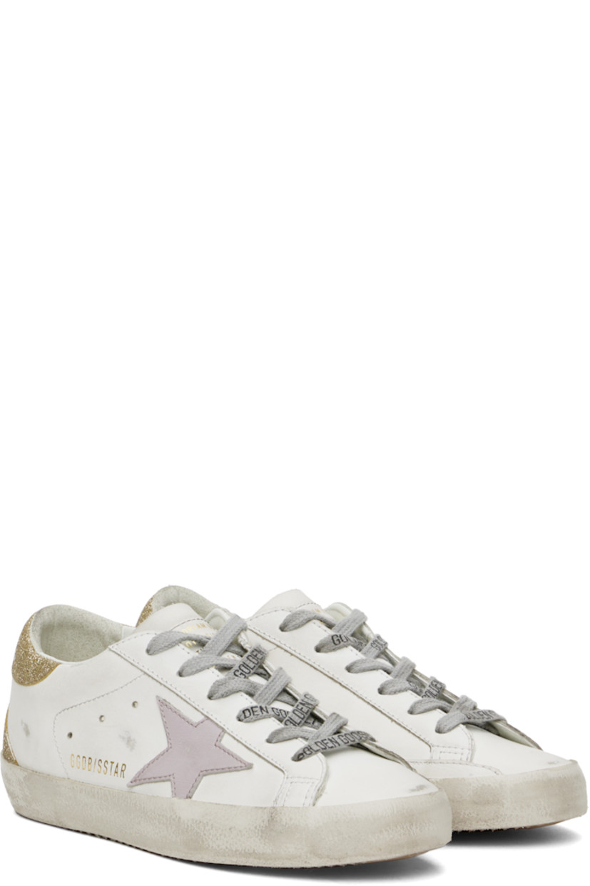 Low-top buffed leather sneakers in white, purple, and gold tone.

· Distressing and smudging throughout
· Lace-up closure
· Logo stamp at tongue
· Padded collar
· Signature star appliqué at outer side
· Logo stamp at outer side
· Perforated detailing at sides
· Logo embossed at glittered heel tab
· Buffed leather, suede, and terrycloth lining
· Textured rubber midsole
· Treaded rubber sole

Supplier color: White/Lilac/Gold