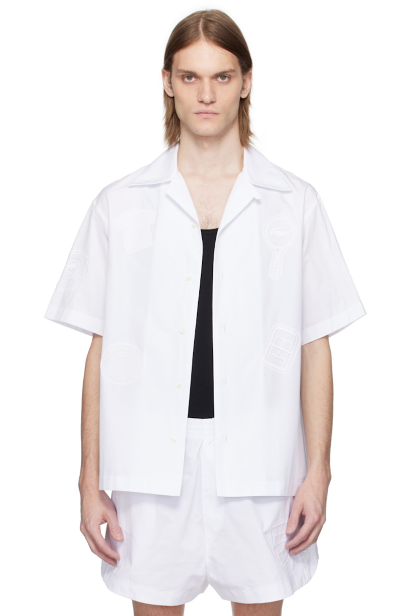 Cotton poplin shirt. Embroidered logo graphic appliqués throughout.

· Button fastening at open spread collar
· Button closure
· Embroidered logo patch at back collar
· Twin pleats at yoke
· Mother-of-pearl hardware

Supplier color: White