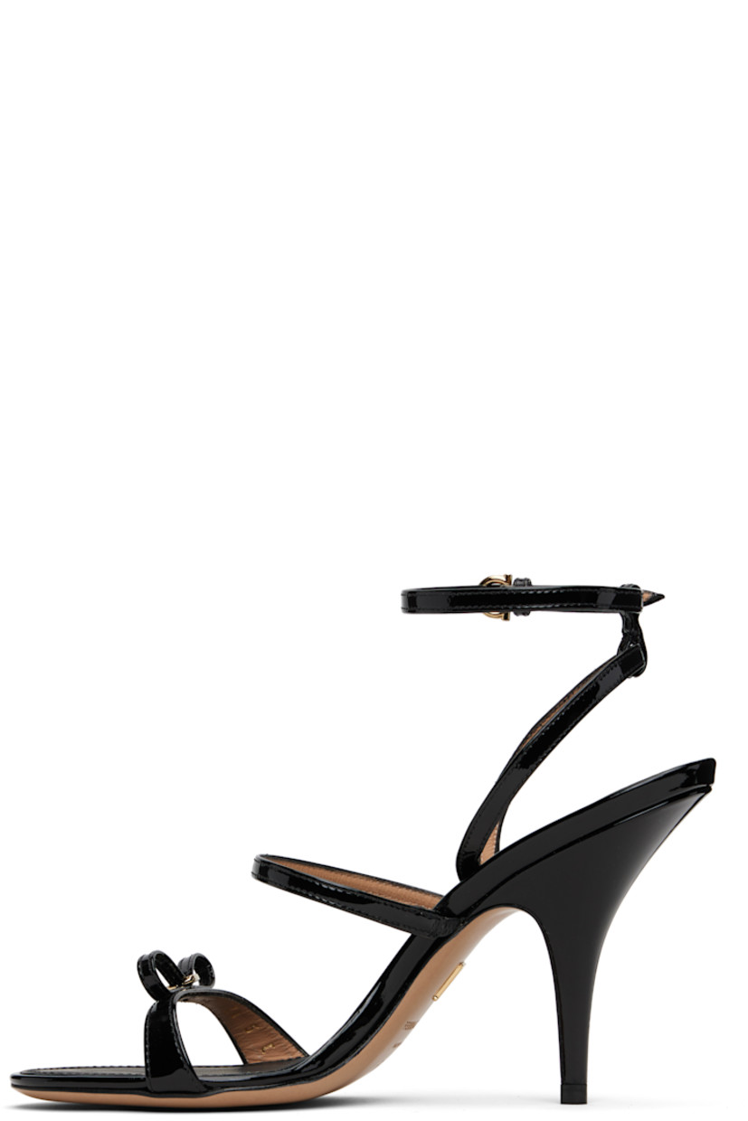 Patent leather heeled sandals.

· Open toe 
· Straps and logo-engraved bow accent at vamp
· Adjustable pin-buckle ankle strap
· Logo stamp at padded footbed
· Covered stiletto heel 
· Leather sole with rubber injections
· Logo hardware at sole
· Gold-tone hardware
· Heel: H3.5"

Supplier color: Nero/Vernice nero