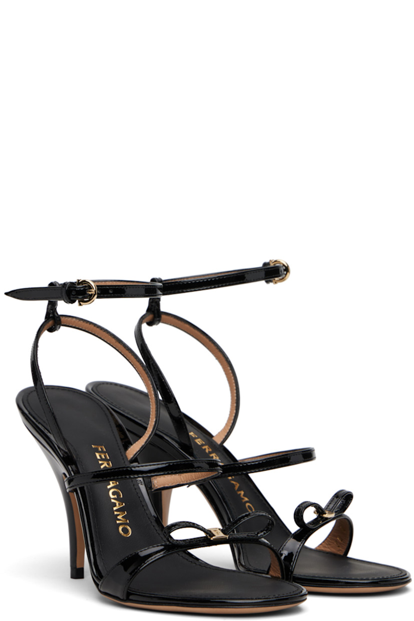 Patent leather heeled sandals.

· Open toe 
· Straps and logo-engraved bow accent at vamp
· Adjustable pin-buckle ankle strap
· Logo stamp at padded footbed
· Covered stiletto heel 
· Leather sole with rubber injections
· Logo hardware at sole
· Gold-tone hardware
· Heel: H3.5"

Supplier color: Nero/Vernice nero