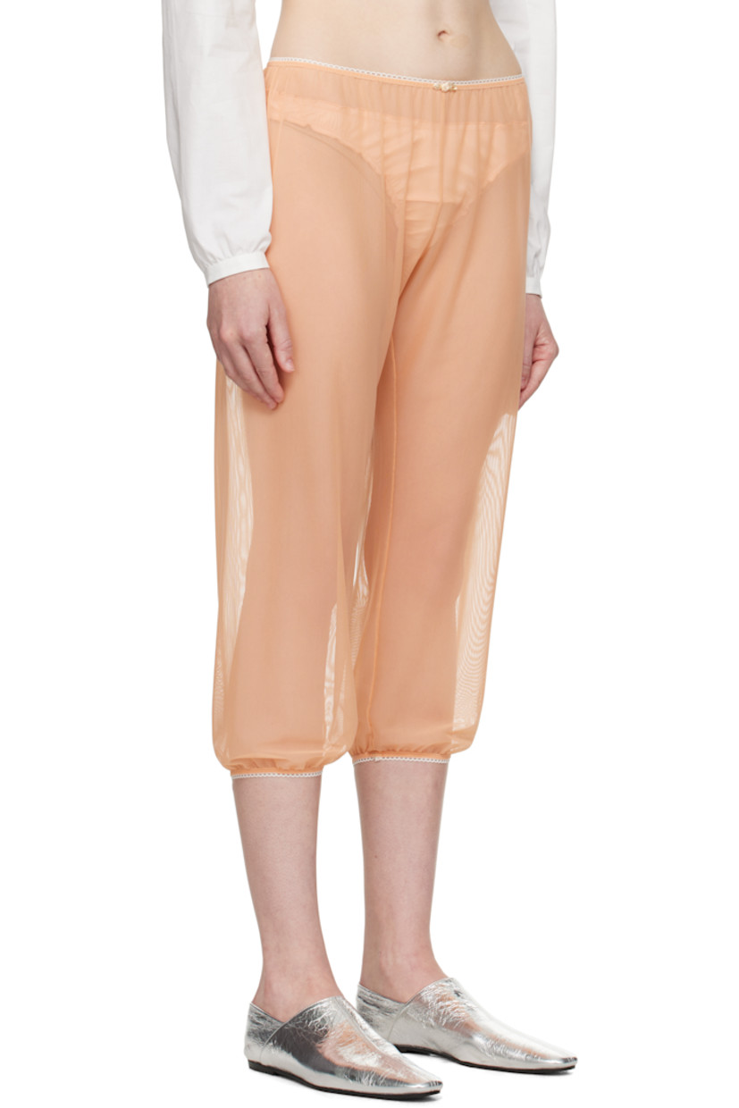 Sheer nylon tulle trousers.

· Scalloped edge at elasticized waistband and cuffs
· Floral appliqué at front waistband
· Cropped legs

Supplier color: Peach