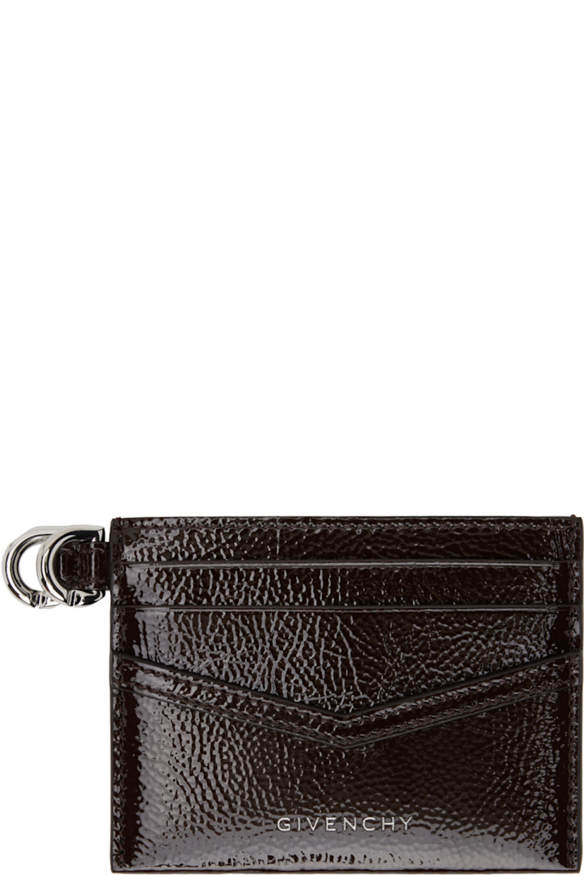 Tumbled patent calfskin card holder in brown. 

· Logo stamp at face
· Six card slots
· Central note slot 
· D-ring at side
· Plain-woven lining
· H3.25" x W4"

Supplier color: Ebony brown