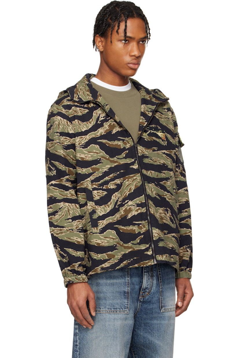 Cotton canvas jacket. Camouflage pattern printed throughout. 

· Bungee-style drawstring at brimmed hood
· Stand collar
· Zip closure
· Embroidered logo patch at chest
· Welt pockets
· Concealed bungee-style drawstring at hem
· Flap pocket at sleeve
· Elasticized cuffs
· Unlined 
· Logo-engraved oxidized gunmetal-tone hardware

Supplier color: Multicolored