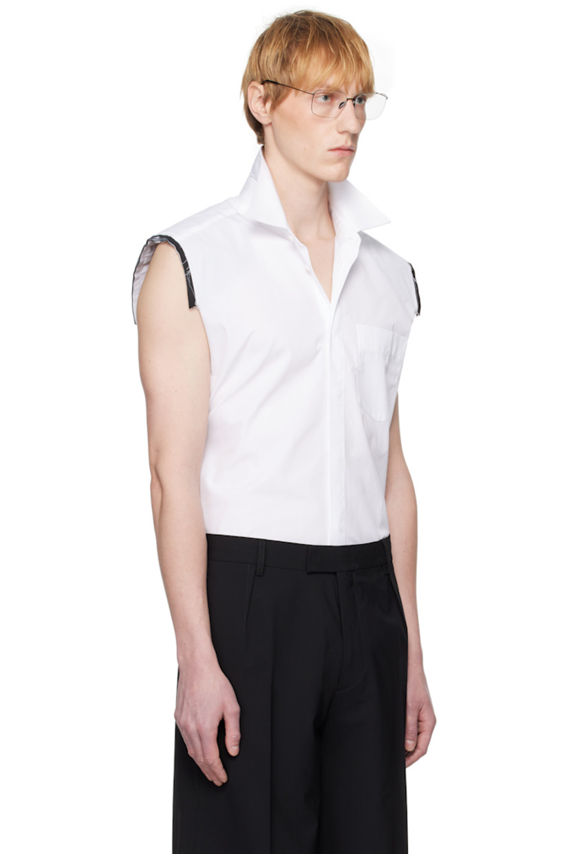 Cotton poplin shirt. 

· Spread collar
· Button closure
· Logo embroidered at patch pocket
· Shirttail hem
· Exposed layered trim at shoulders
· Raw edge at armscyes
· Box pleat at back yoke
· Mother-of-pearl hardware

Supplier color: White