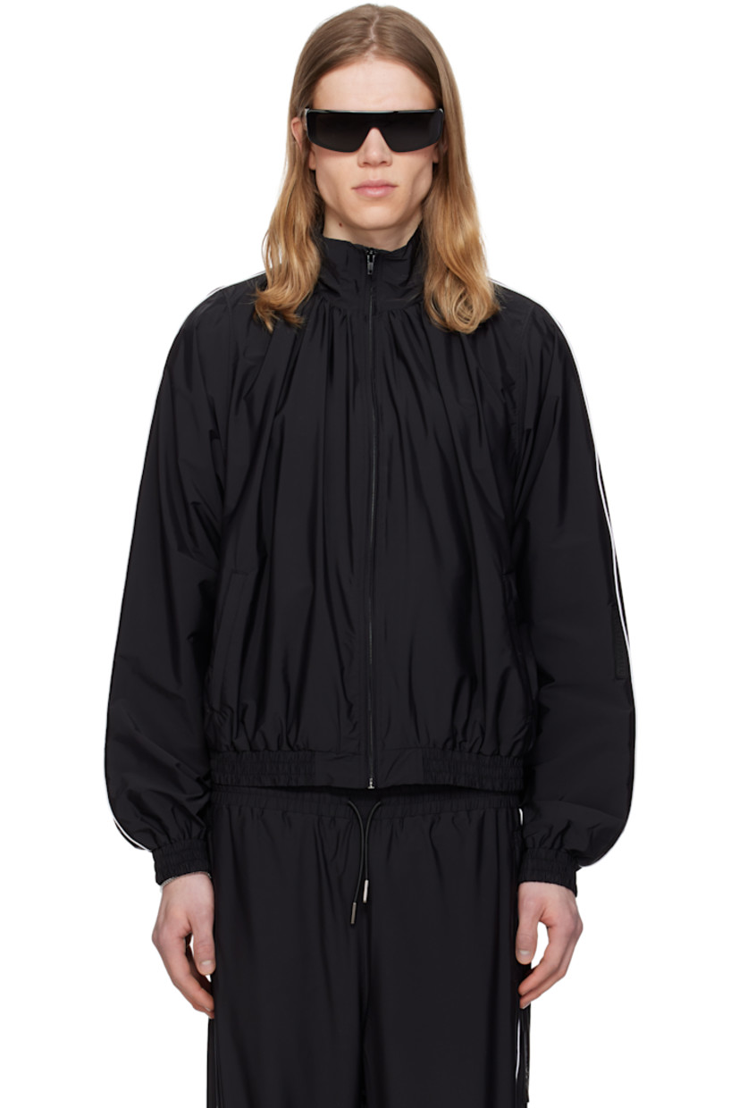 Stretch nylon taffeta track jacket.

· Gathering at stand collar
· Zip closure
· Zip pockets
· Elasticized hem and cuffs
· Piping at sleeves
· Rubberized logo patch at sleeve
· Full cotton jersey lining

Supplier color: Black