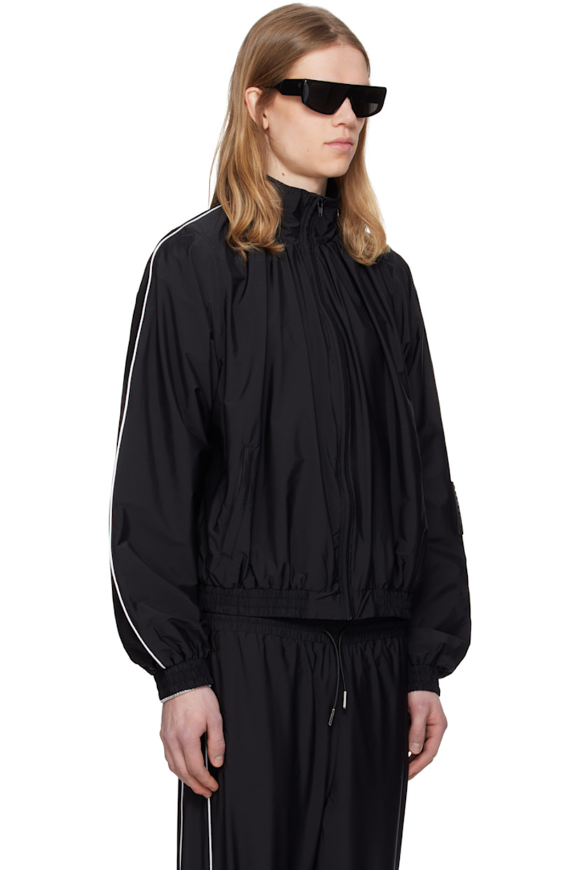 Stretch nylon taffeta track jacket.

· Gathering at stand collar
· Zip closure
· Zip pockets
· Elasticized hem and cuffs
· Piping at sleeves
· Rubberized logo patch at sleeve
· Full cotton jersey lining

Supplier color: Black