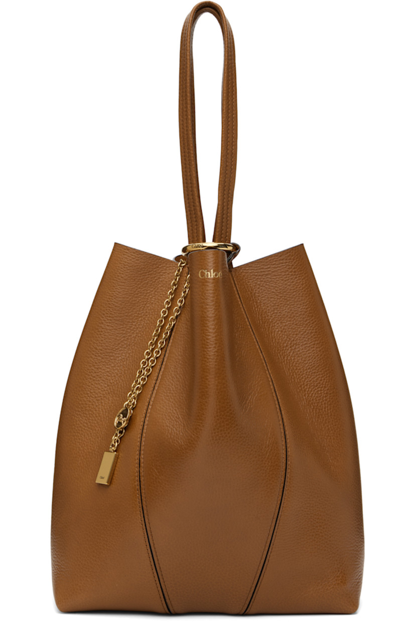 Grained leather tote in brown.

· Twin carry handles
· Detachable logo charms at handle base
· Logo stamp at face
· Lanyard clasp at interior
· H12" x W10.5" x D5.5"

Supplier color: Clay brown
