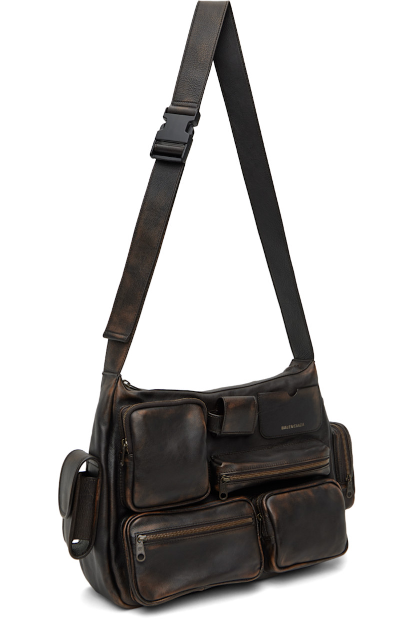 Grained calfskin messenger bag in brown.

· Fading throughout
· Flap and zip pockets throughout
· Adjustable crossbody strap
· Silver-tone logo stamp at face and back
· Card slot and AirPods Pro compartment at face
· Zip pocket at back face
· Zip closure
· Cotton canvas lining
· Logo-engraved antiqued gold-tone hardware
· H10" x W13" x D4"

Supplier color: Brown