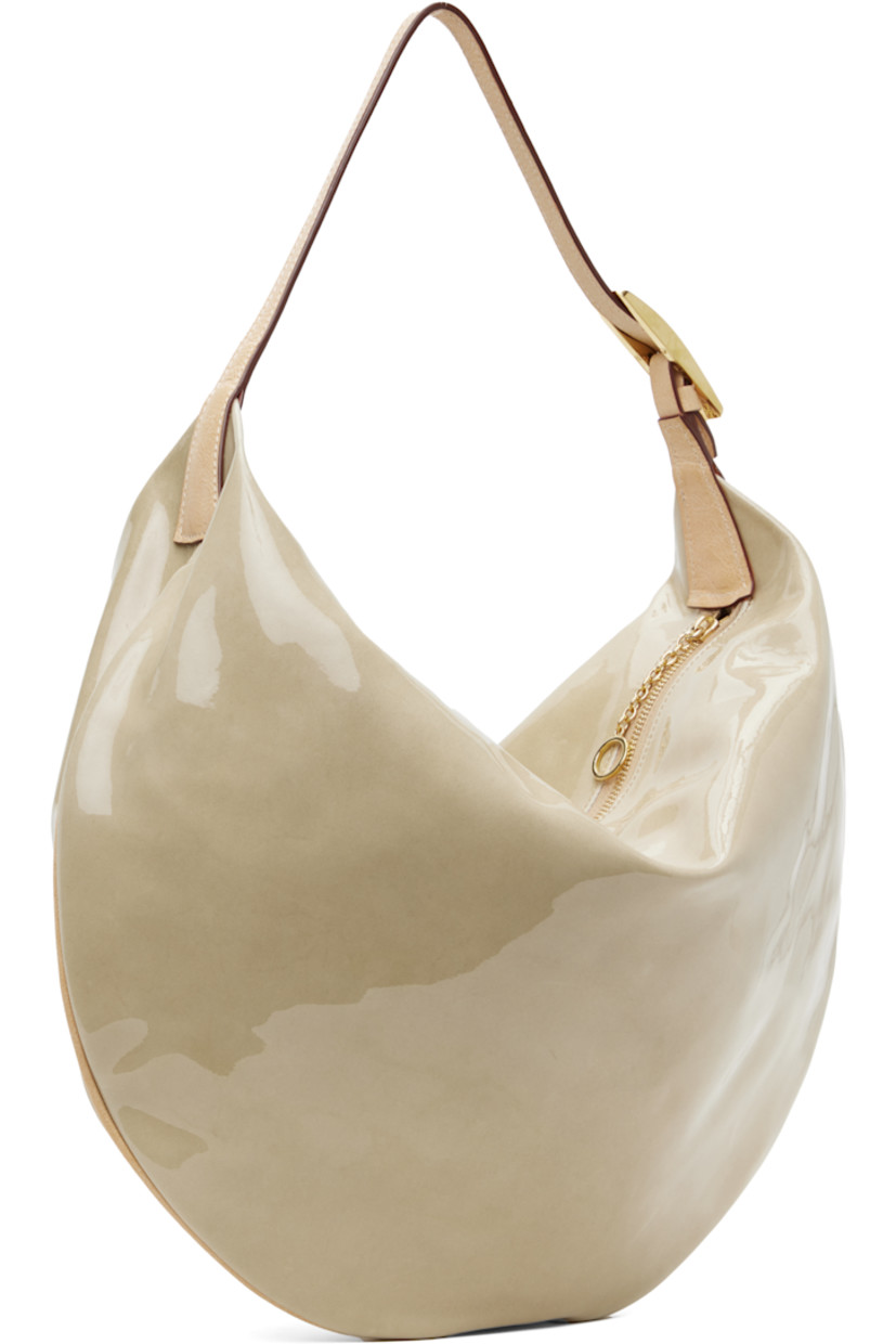 Patent leather shoulder bag in beige.

· Adjustable grained leather shoulder strap
· Zip closure
· Faux-suede lining
· Gold-tone hardware
· H13" x W17" x D3.5"

Supplier color: Palo santo