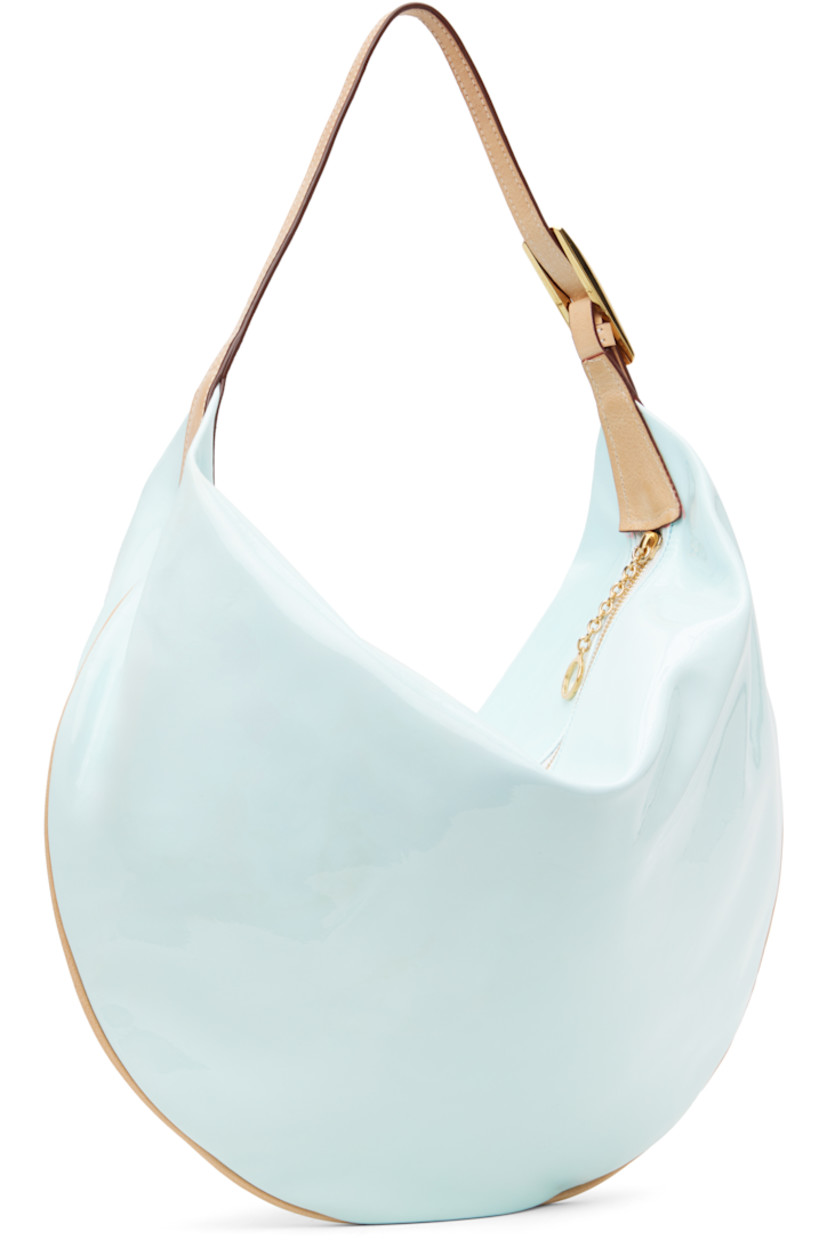 Patent leather shoulder bag in blue.

· Adjustable grained leather shoulder strap
· Zip closure
· Faux-suede lining
· Gold-tone hardware
· H13" x W17" x D3.5"

Supplier color: Frozen blue