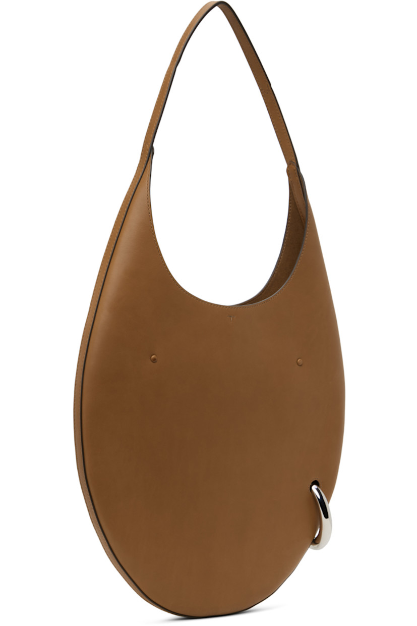 Buffed leather shoulder bag in tan.

· Fixed shoulder strap
· Silver-tone O-ring at side
· Self-tie closure
· Zip pocket at interior
· Faux-suede lining
· H12" x W12.5" x D1"
· Total height: H23"
 
Supplier color: Aged tan