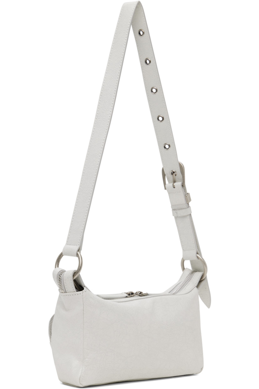 Cracked leather shoulder bag in off-white.

· Adjustable pin-buckle shoulder strap
· Zip pockets at face
· Logo embossed at face
· Two-way zip closure
· Zip and patch pocket at interior
· Logo-patterned moiré lining
· Logo-engraved antiqued silver-tone hardware
· H5" x W9" x D3"

Supplier color: Off white cracked