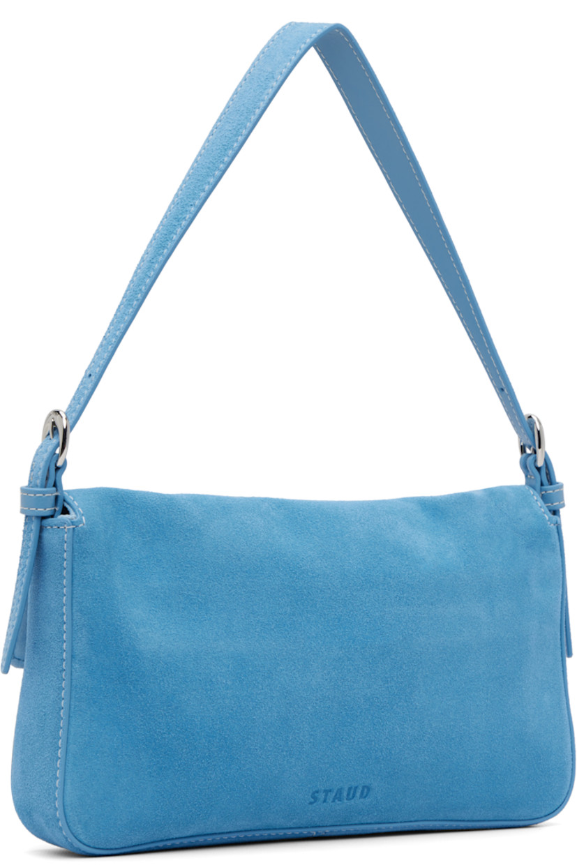 Suede shoulder bag.

· Adjustable shoulder strap
· Logo embossed at back face
· Pin-buckle hardware at magnetic press-stud flap
· Zip pocket at interior
· Logo-engraved silver-tone hardware
· H5" x W9.75" x D1.5"

Supplier color: Staud blue