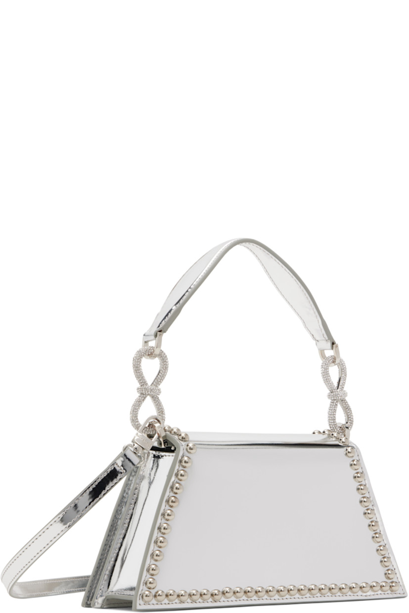 Patent leather top handle bag in silver tone.

· Studs throughout
· Detachable carry handle
· Crystal-cut bow accents at carry handle
· Adjustable and detachable crossbody strap
· Bow accent at face 
· Magnetic press-stud flap 
· Card slot at interior
· Twill lining 
· Logo-engraved silver-tone hardware
· H4.5" x W9.5" x D2"

Supplier color: Silver
