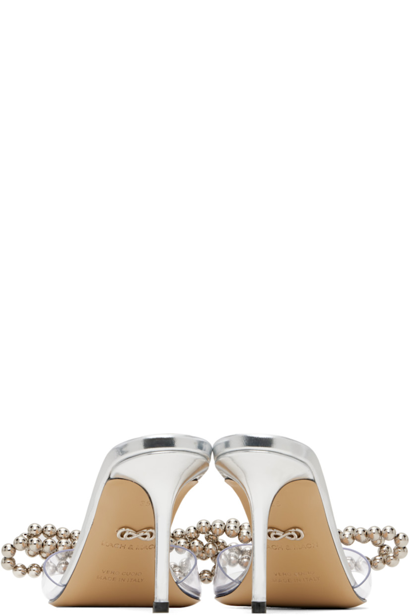 Transparent vinyl and patent leather mules in metallic silver tone. 

· Open toe
· Beaded bow with crystal-cut accents at vamp
· Logo stamp at padded footbed
· Buffed leather lining
· Covered stiletto heel with rubber injection
· Leather sole
· Heel: H2.75"

Supplier color: Transparent/Silver