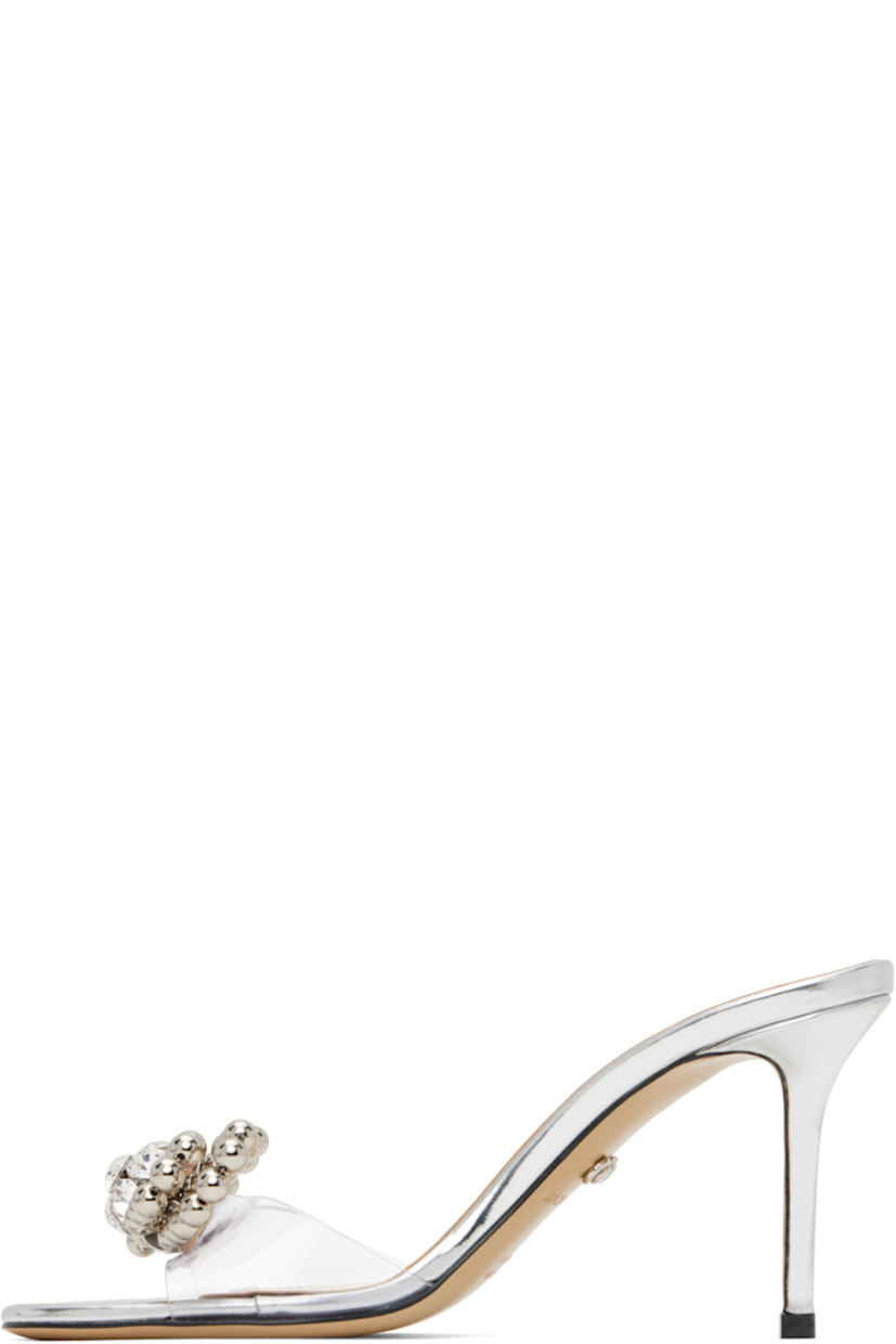 Transparent vinyl and patent leather mules in metallic silver tone. 

· Open toe
· Beaded bow with crystal-cut accents at vamp
· Logo stamp at padded footbed
· Buffed leather lining
· Covered stiletto heel with rubber injection
· Leather sole
· Heel: H2.75"

Supplier color: Transparent/Silver