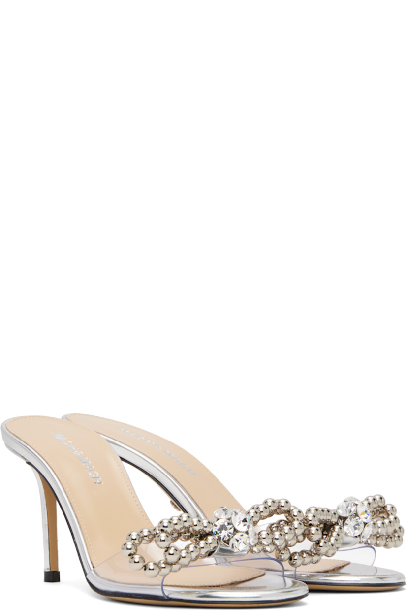 Transparent vinyl and patent leather mules in metallic silver tone. 

· Open toe
· Beaded bow with crystal-cut accents at vamp
· Logo stamp at padded footbed
· Buffed leather lining
· Covered stiletto heel with rubber injection
· Leather sole
· Heel: H2.75"

Supplier color: Transparent/Silver