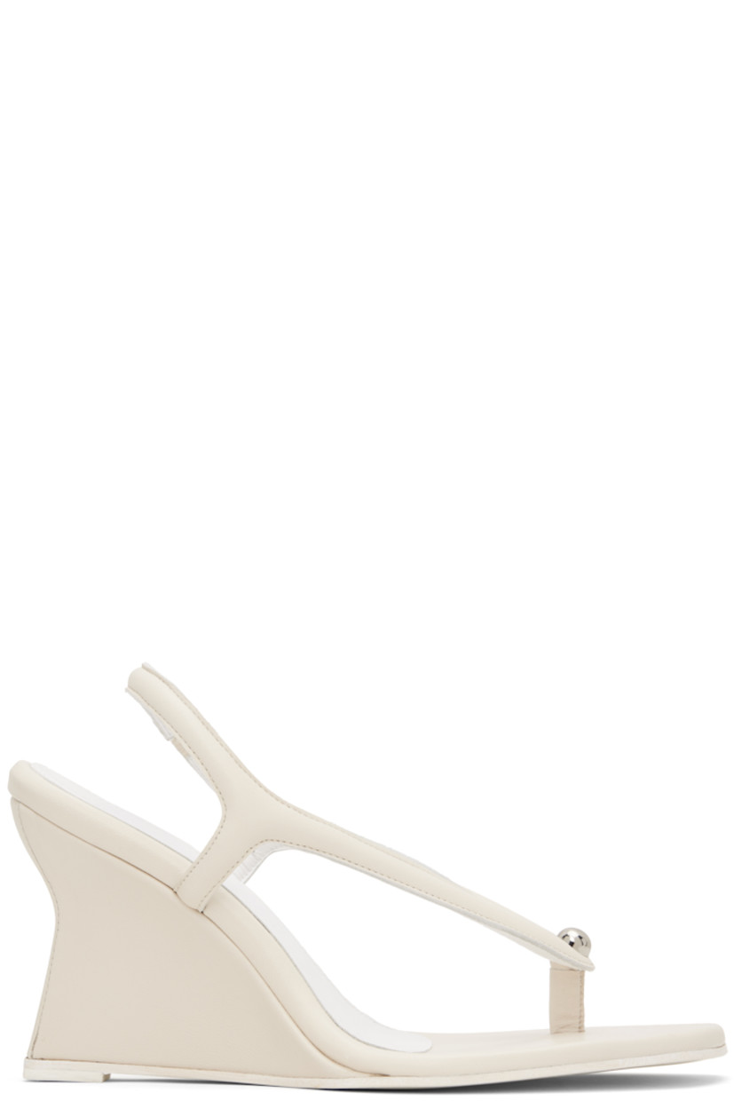 Buffed leather heeled sandals in off-white.

· Open pointed toe
· Thong-style strap and stud at vamp
· Partially elasticized slingback strap
· Logo embossed at padded footbed
· Covered wedge heel with rubber injection
· Leather sole
· Heel: H3.5"

Supplier color: Cream