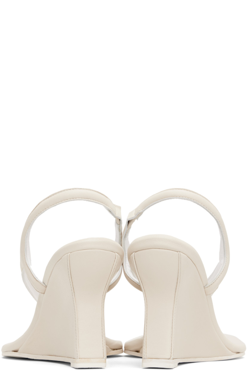Buffed leather heeled sandals in off-white.

· Open pointed toe
· Thong-style strap and stud at vamp
· Partially elasticized slingback strap
· Logo embossed at padded footbed
· Covered wedge heel with rubber injection
· Leather sole
· Heel: H3.5"

Supplier color: Cream